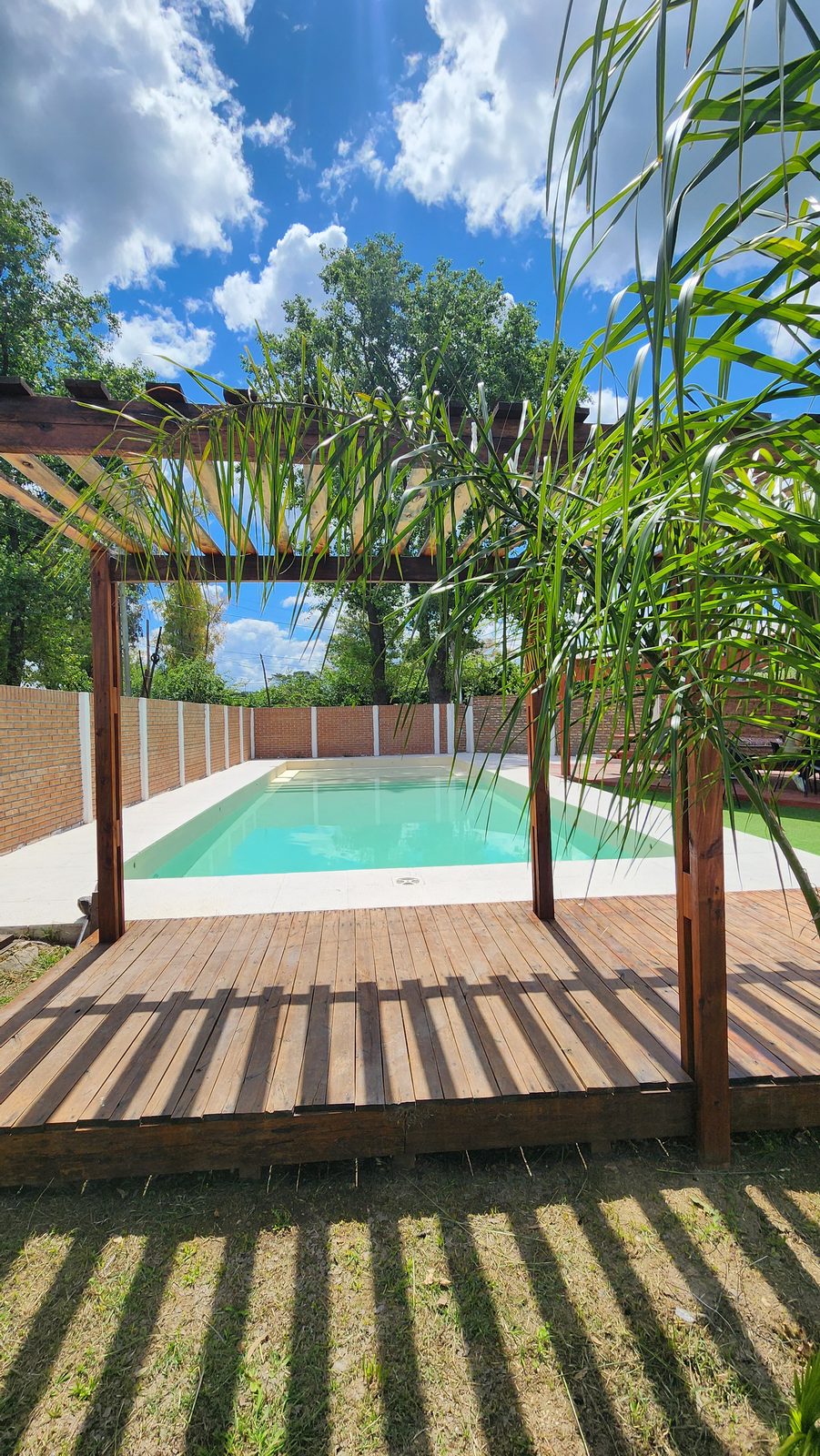 Deck y pérgola de madera junto a la pileta de Quinta El Arroyo