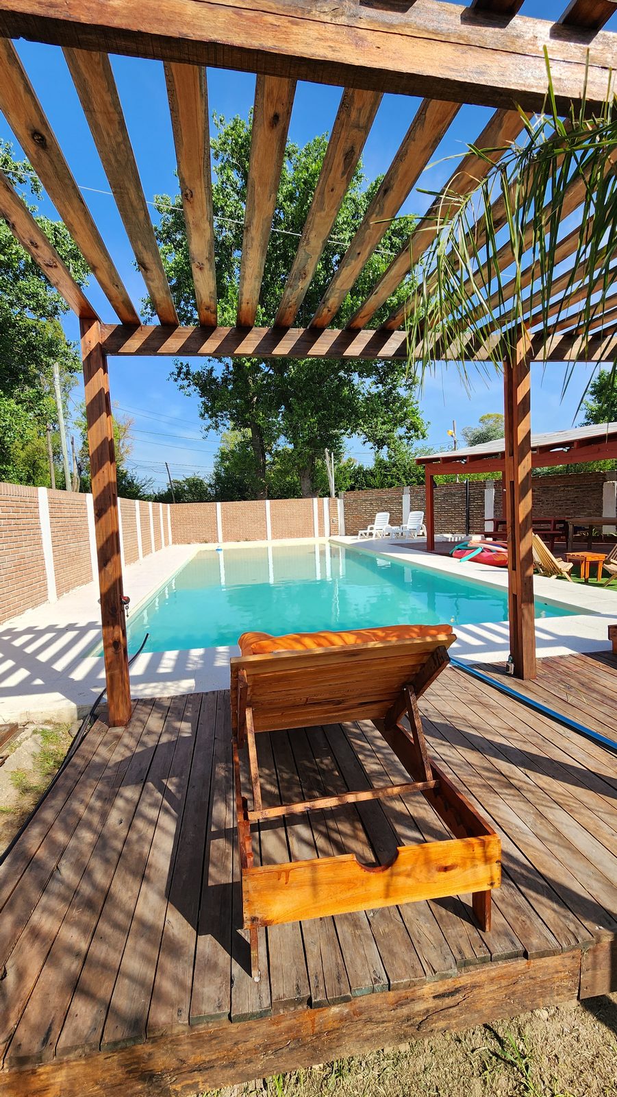 Pérgola con reposeras naranjas junto a la pileta en Quinta El Arroyo